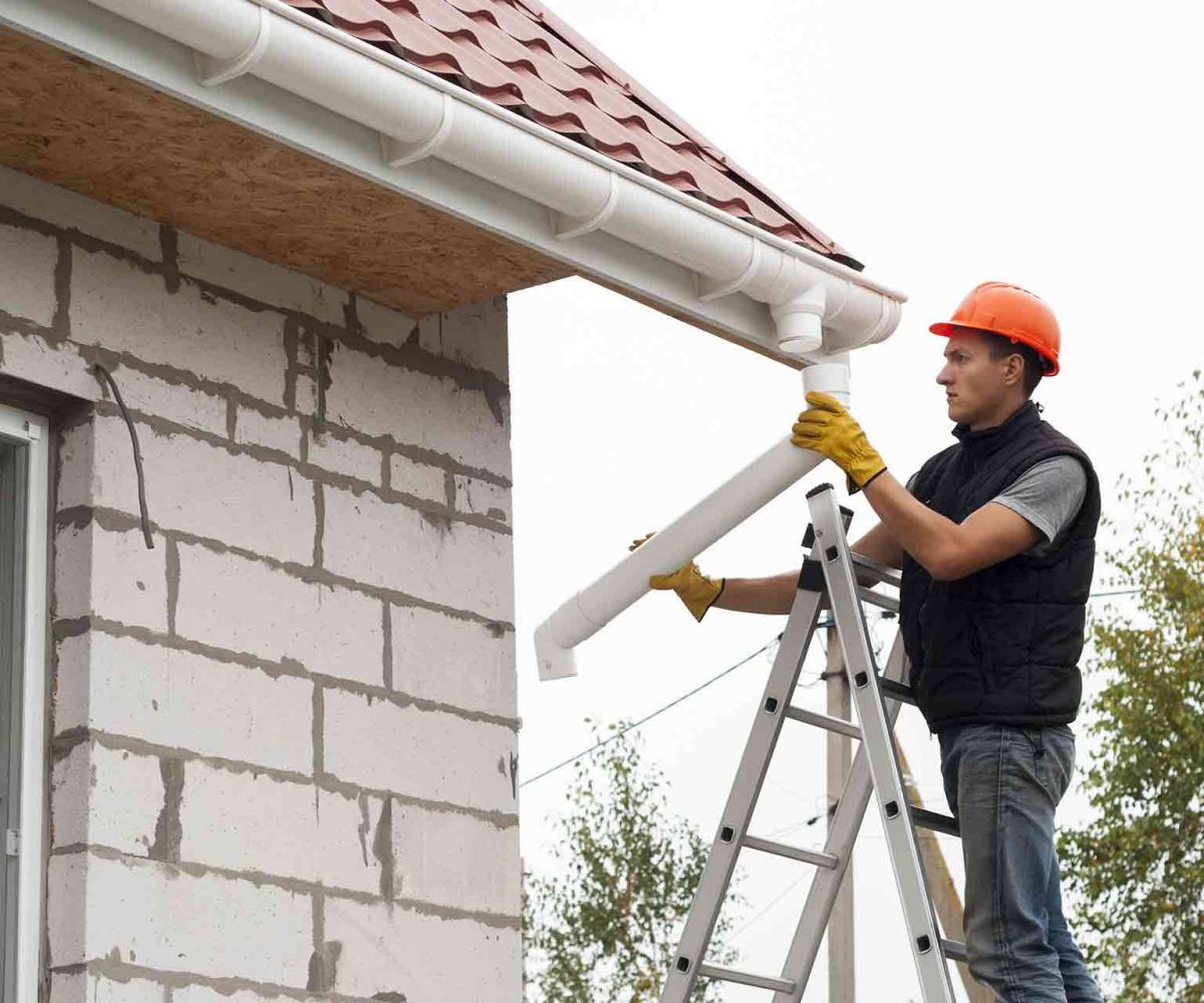 Feature-How-to-find-a-gutter-installer A man on a ladder doing a gutter installation.